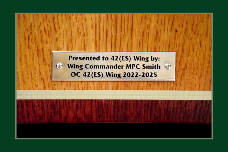 Polished brass dedication plaque engraved with black lettering.